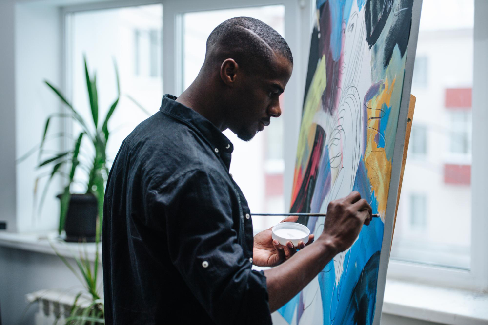 A man painting at an easel in a bright living space